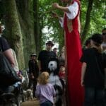 Gaukler mit Hund auf Stelzen