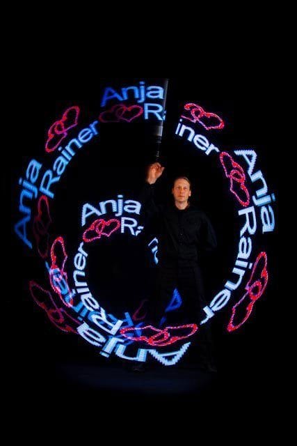 LED-Künstler Detlef Vogt dreht LED Stäbe und zeigt „Anja“ und „Rainer“ mit leuchtenden Mustern auf dunklem Hintergrund.