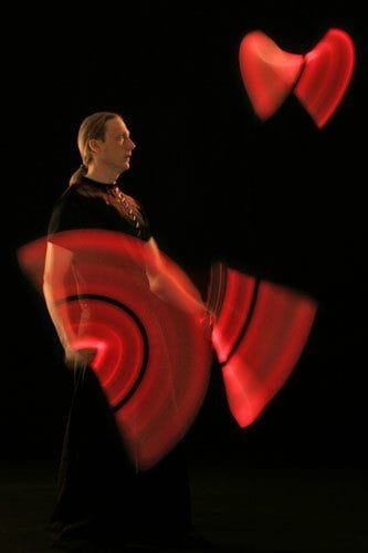 Lichtjonglage mit 3 Leuchtkeulen in der Dunkelheit