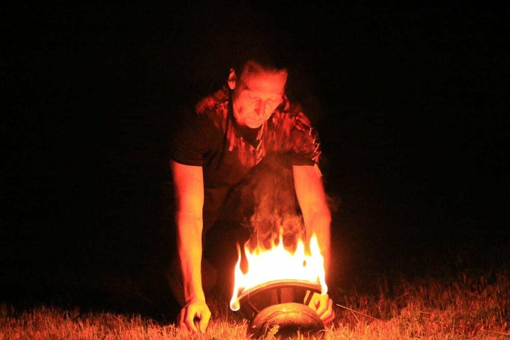 Der Feuerkünstler kniet vor einem brennenden Helm