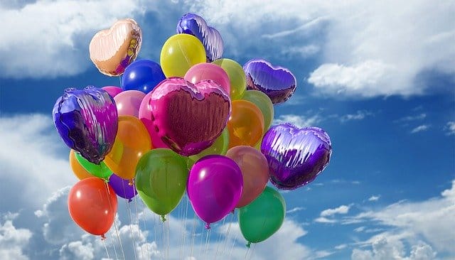 Bunte Luftballons schweben für Geburtstagsüberraschungen am Himmel.