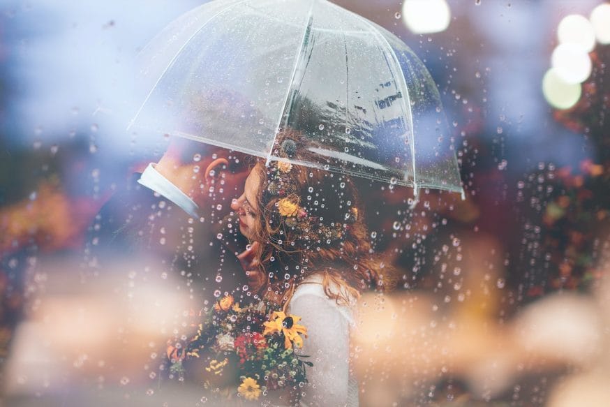 Braut und Bräutigam bei Regen unter einem Schirm