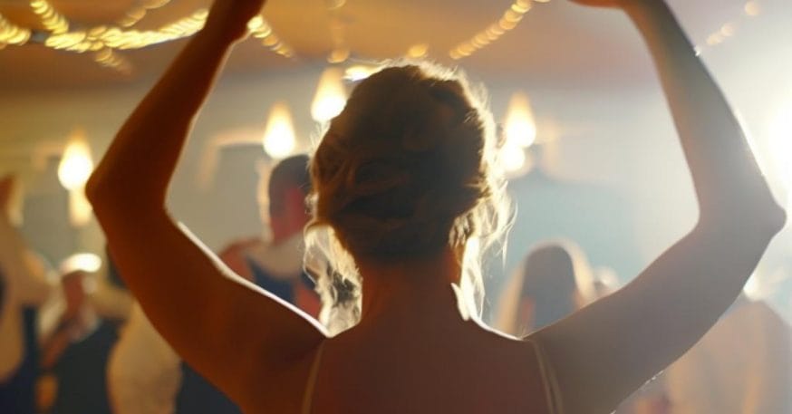 Eine Frau tanzt bei einer Hochzeit zum Unterhaltungsprogramm mit erhobenen Armen.