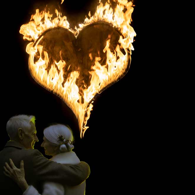 Ein Paar, das sich vor einem feurigen Herzen an Ihrer Feuerhochzeit umarmt.