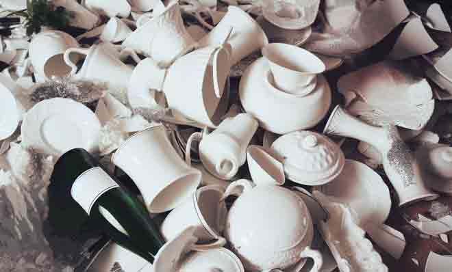 Ein Haufen zerbrochener weißer Teller und Tassen aus Porzellan