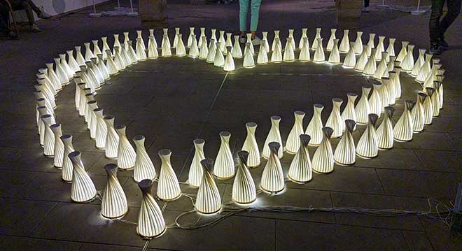 Herzförmiges Arrangement leuchtender dekorativer Laternen auf dem Boden.